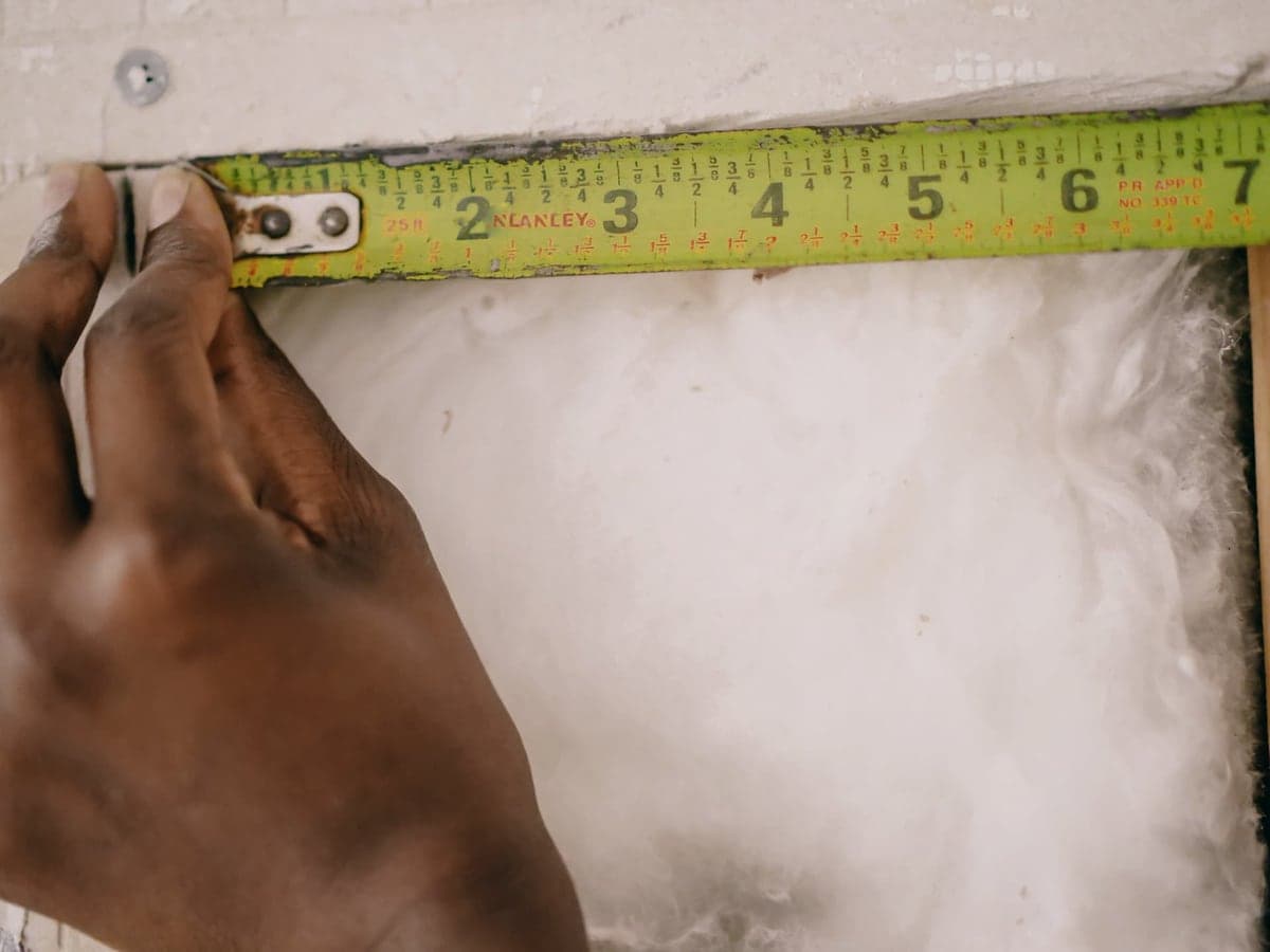 A storage tote being measured with a tape measure
