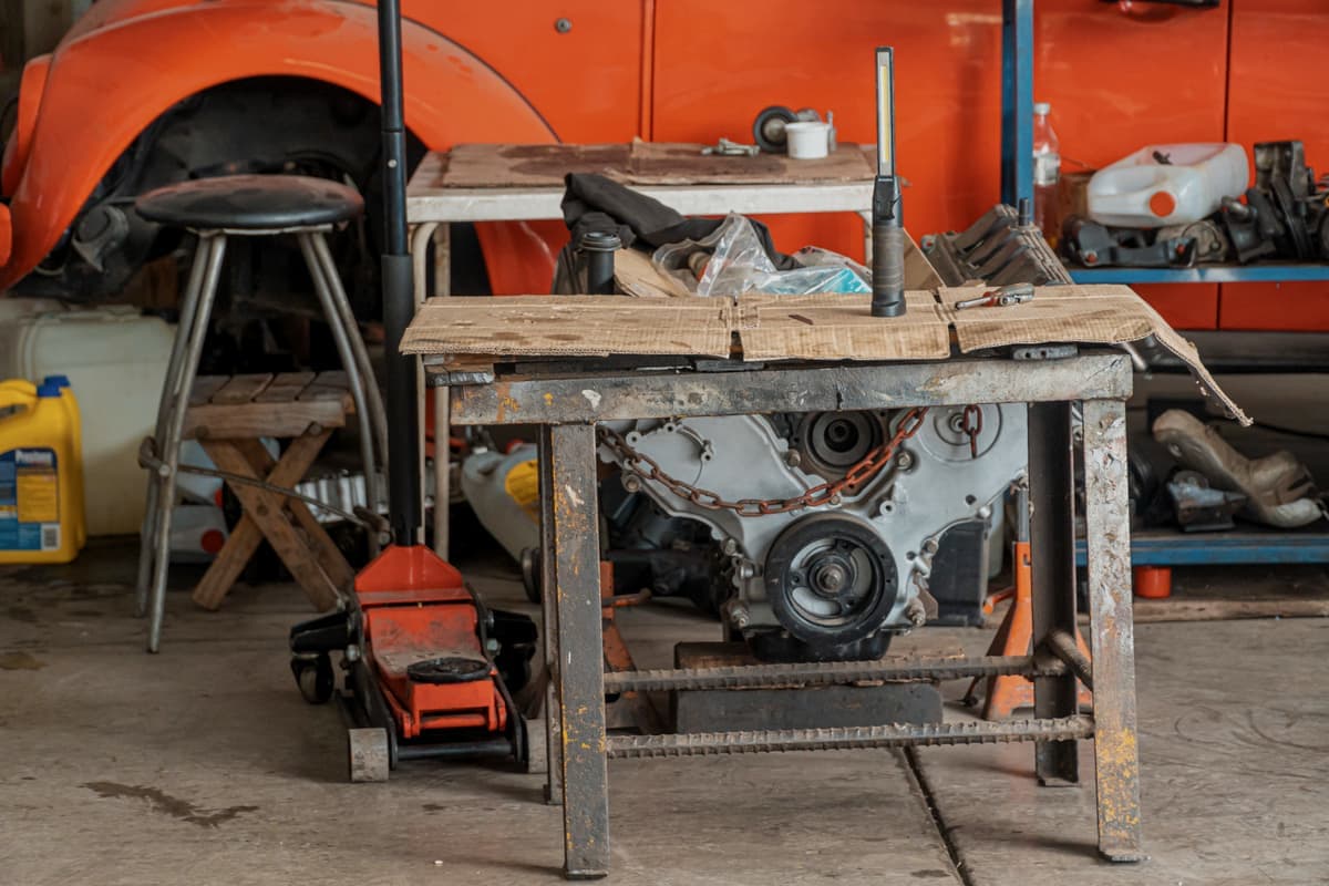 A workshop table holding an engine and tools in a garage