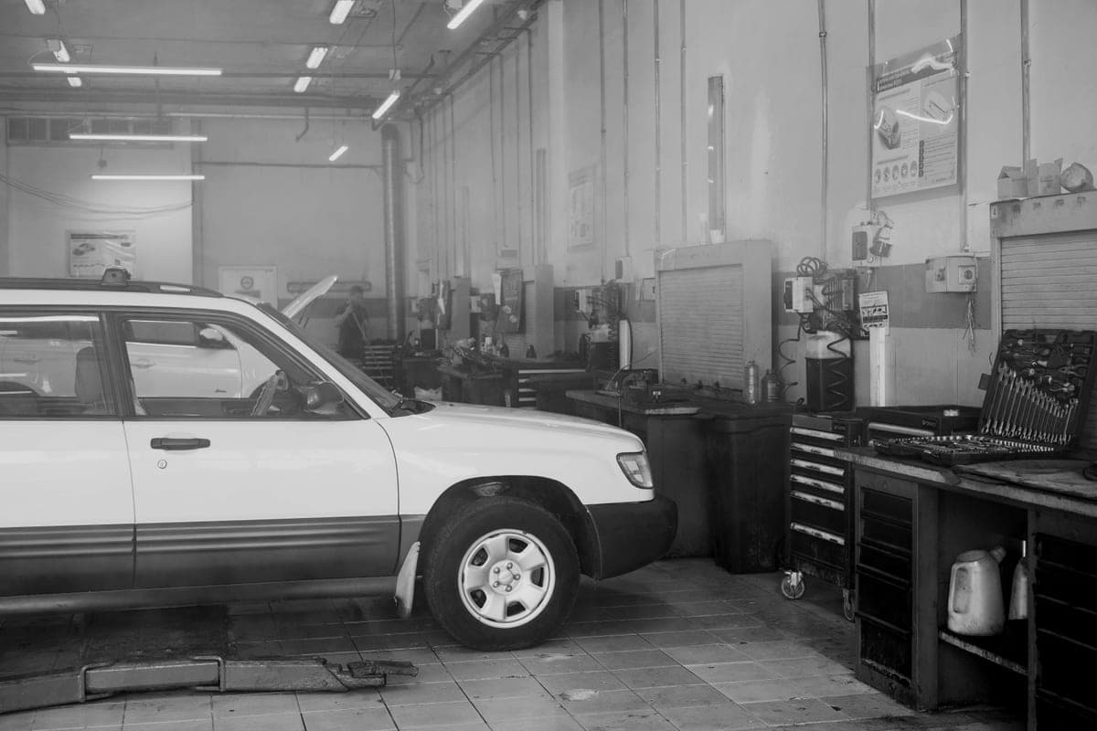 A garage workshop with tool cabinets along the wall beside a parked car