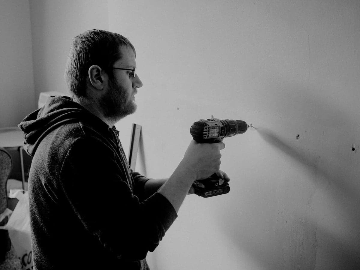 A person on a ladder working on a garage ceiling with a power drill
