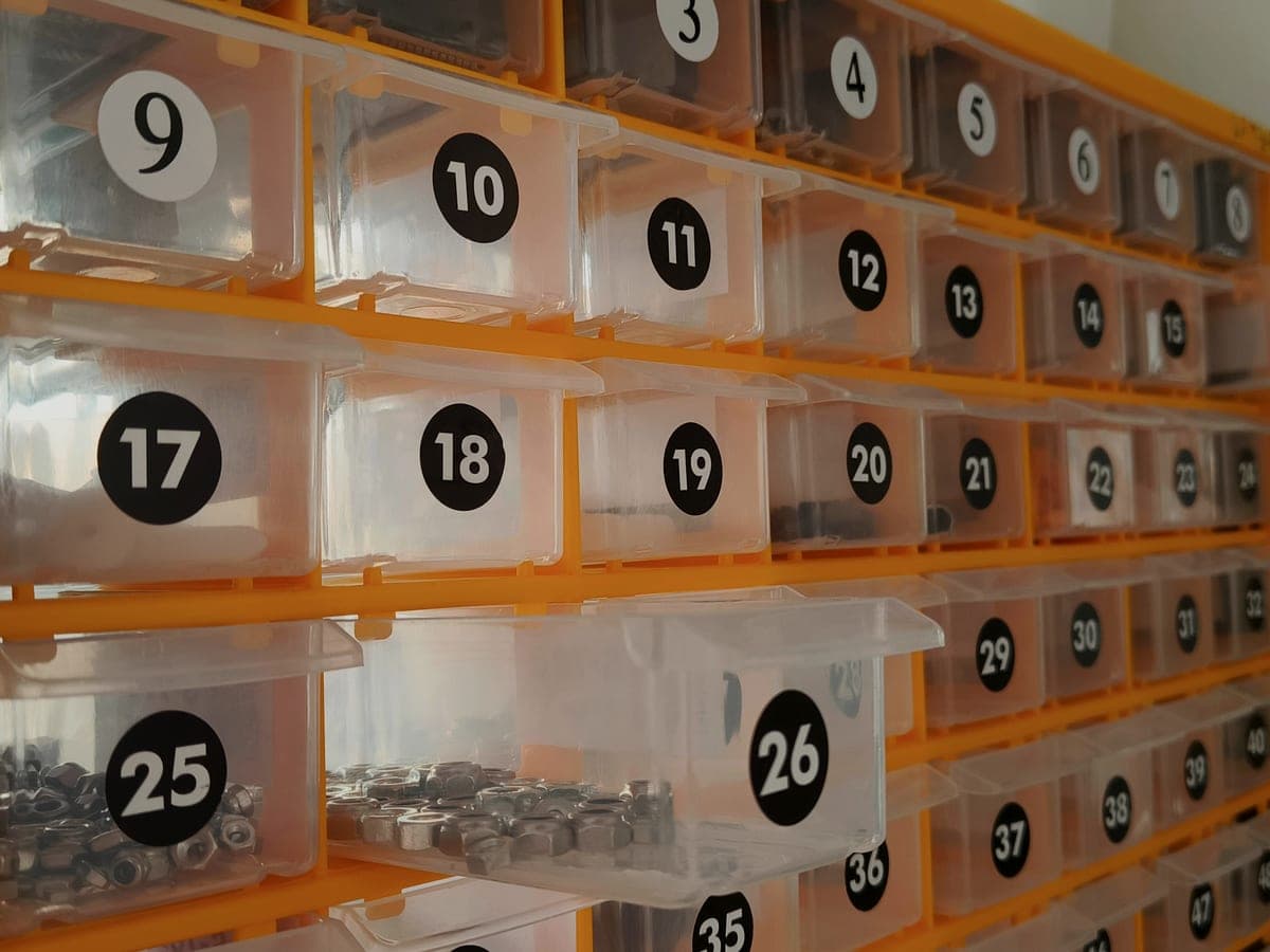 A plastic storage shelving system holding labeled bins in a workshop