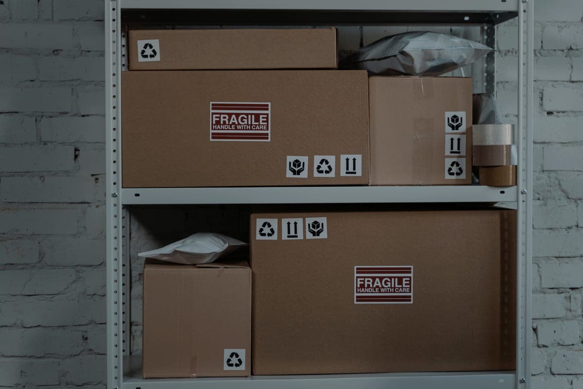 Cardboard boxes stacked on a light steel shelving unit in a storage room