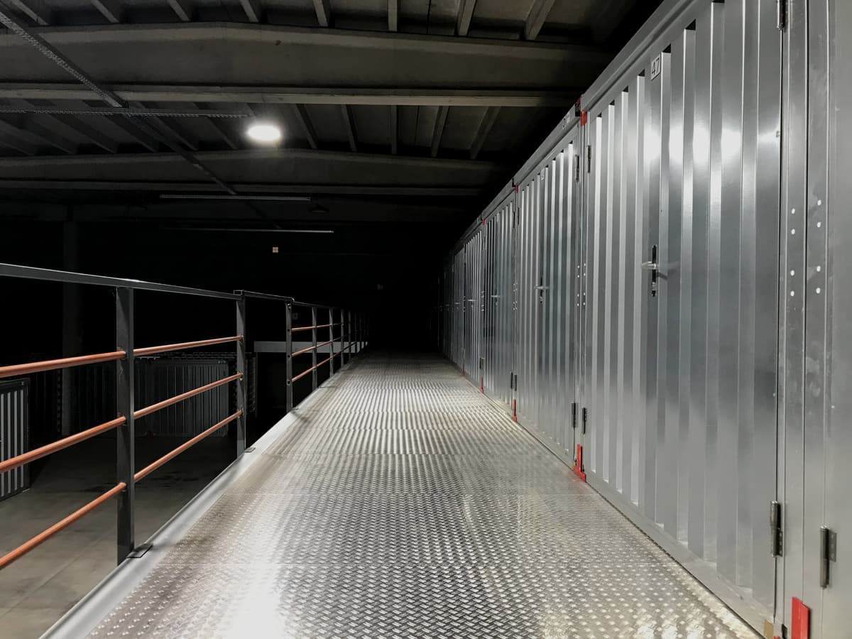 An empty industrial corridor lined with steel storage unit doors