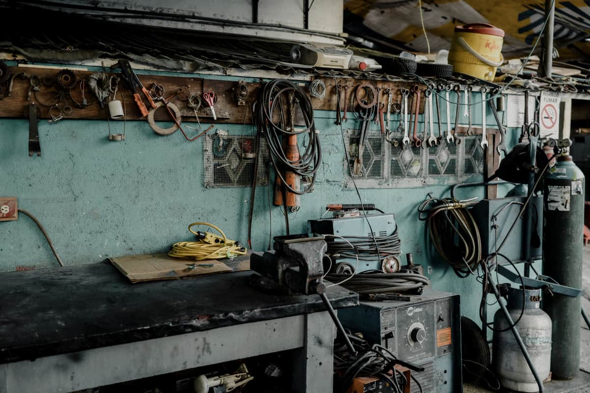 Coiled cords and hoses hanging on hooks above a workshop bench