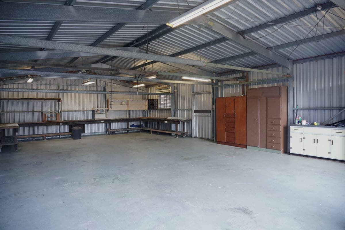 An empty steel-walled industrial garage with storage cabinets and workbenches