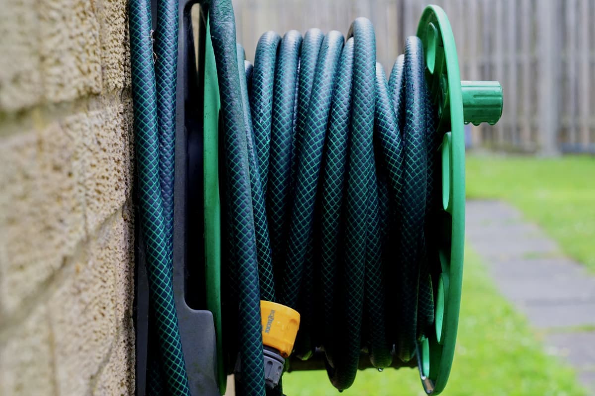 A coiled garden hose on a wall-mounted reel