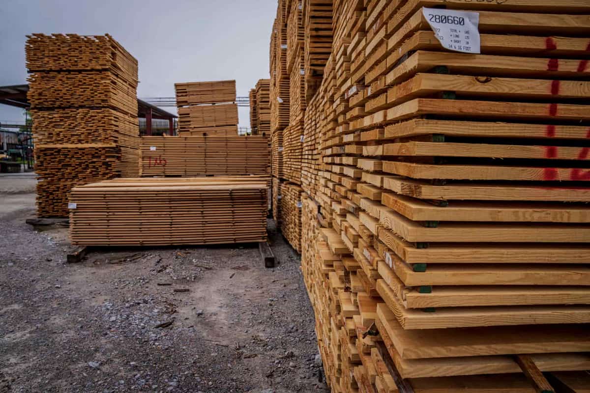 Stacked lumber and plywood boards stored against a wall