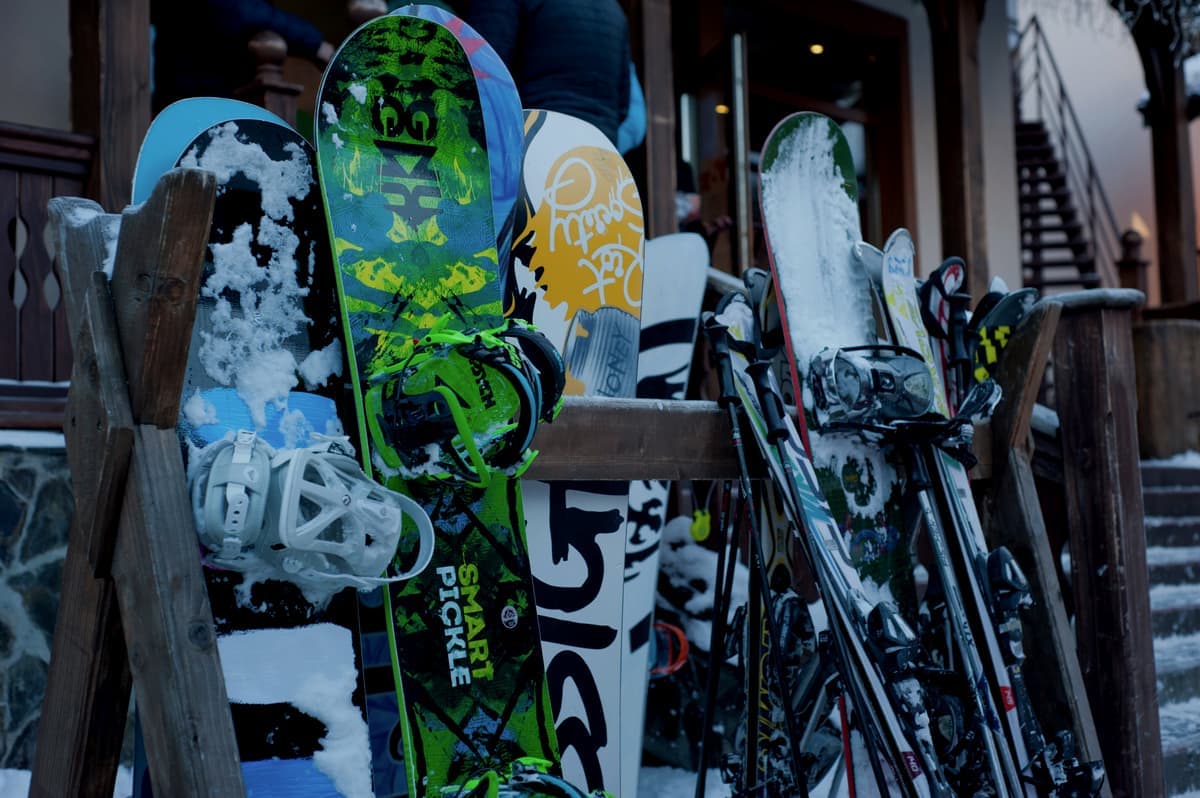 Skis and snowboards standing in a wooden rack outside a lodge
