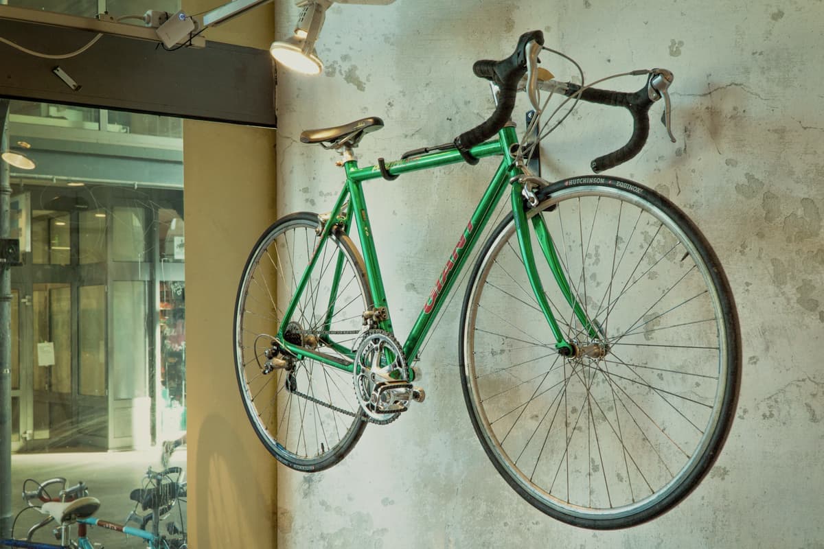 A bicycle hanging vertically from a wall mount indoors