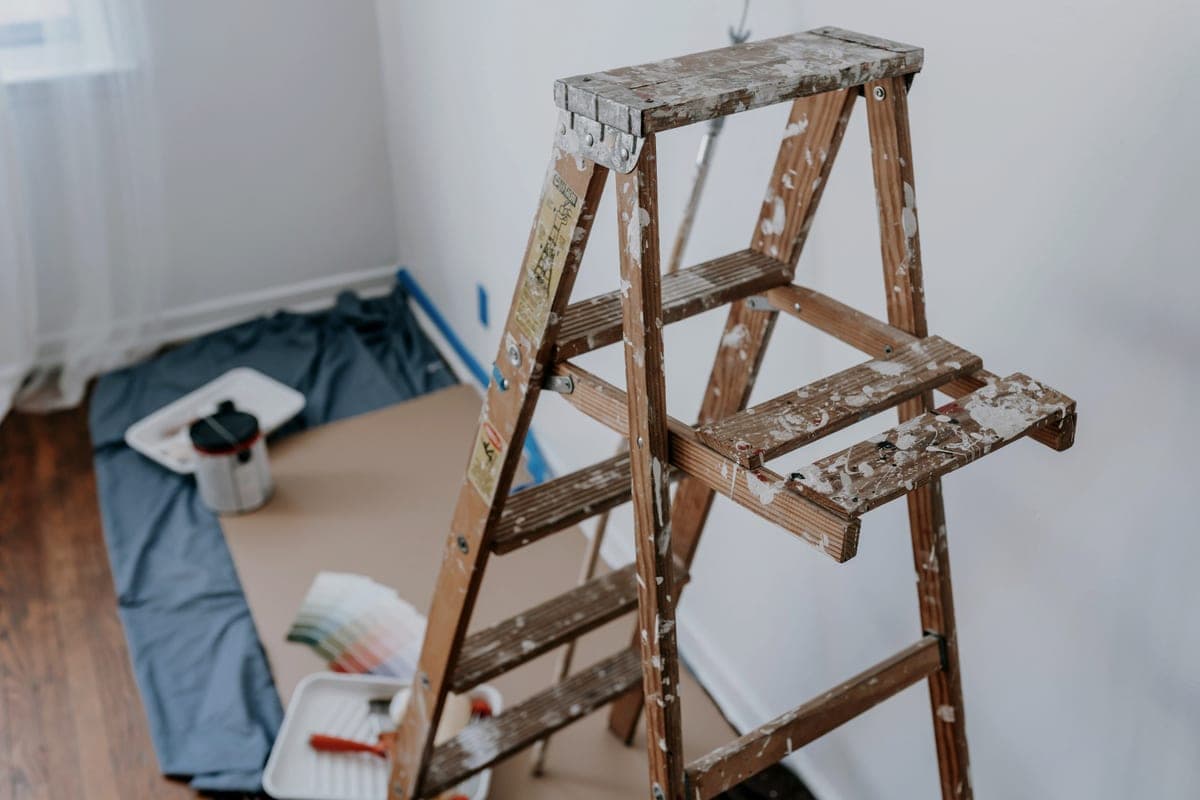 A paint-spattered wooden step ladder standing open in a room