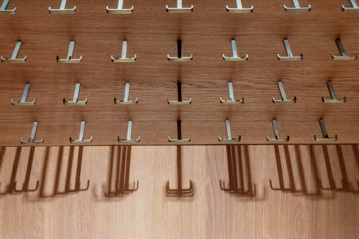 Rows of metal hooks mounted on a wooden wall panel