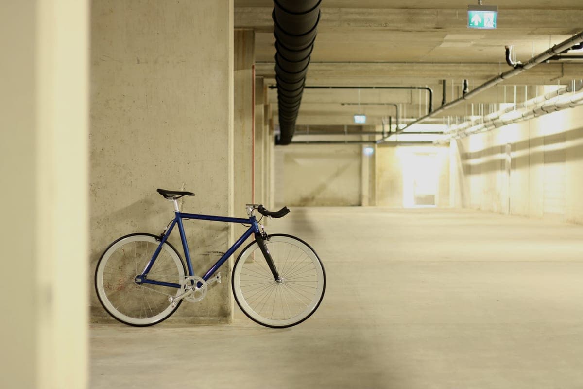 A bicycle standing against a concrete wall in a bare room